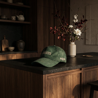 Green cap on a dark countertop with a vase of flowers in the background